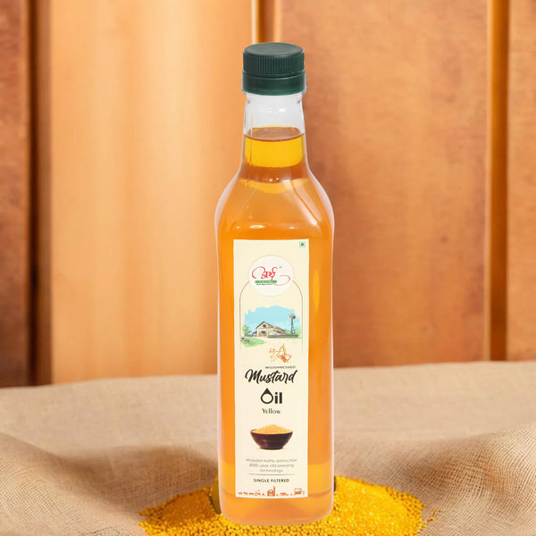 A clear bottle containing yellow mustard oil, with a label displaying the product name and organic certification. The bottle is placed on a wooden surface with a wooden background.