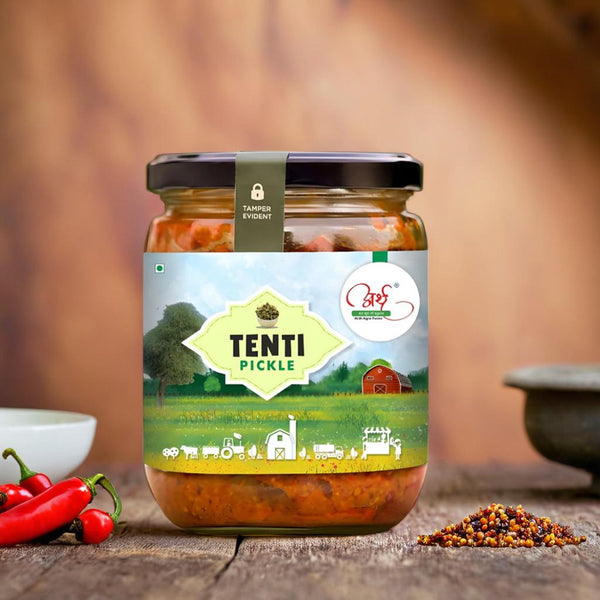 A jar of Authentic Tenti Pickle with a label featuring an illustration of a traditional Indian landscape. The pickle is made using Tenti fruit, traditional spices, and wood-pressed mustard oil.