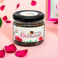 A jar of Mishri Gulkand, Ayurvedic rose preserve with rock sugar, with rose petals around it, presented against a pink background.